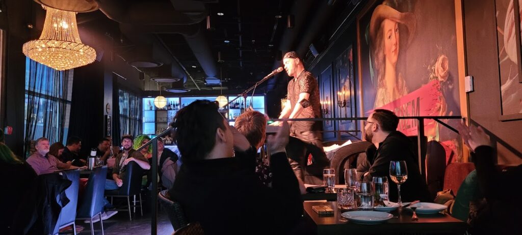Interior view of Friends of Dorothy lounge and bar in Kelowna, with a full house and a musician on stage – photo by Graham Shonfield for Google Reviews